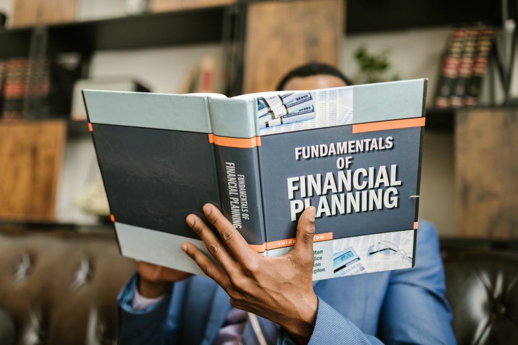 A professional individual in a suit reading Fundamentals of Financial Planning indoors.